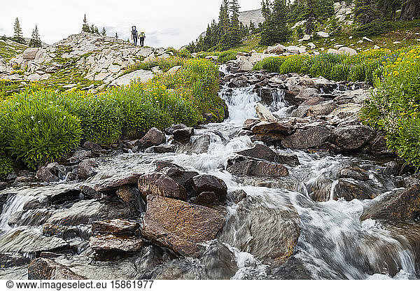 Hikers pass cascade near Pierre Lakes  Elk Mountains  Colorado