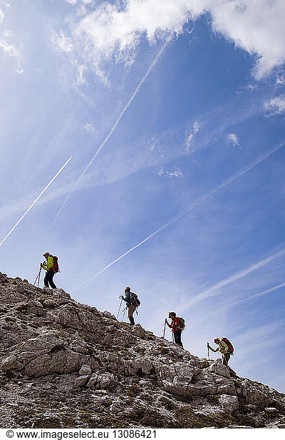 Hikers walking across mountain against sky