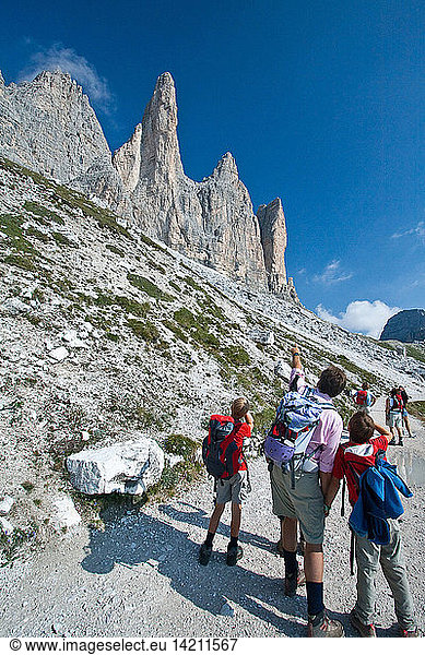 Hikers watch the bold peaks of the Three Peaks from the path that leads to the Lavaredo Refuge  Auronzo of Cadore  Dolomites  Veneto  Italy  Europe
