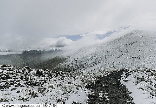 Hiking trail in fresh snow and clouds on Ben Lomond  New Zealand