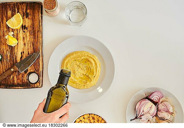 Hinzufügen von Olivenöl zu Hummus  Ansicht von oben