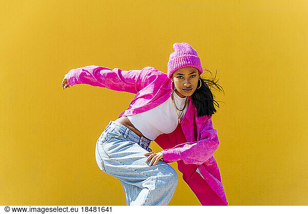 Hip hop dancer dancing in front of yellow wall on sunny day