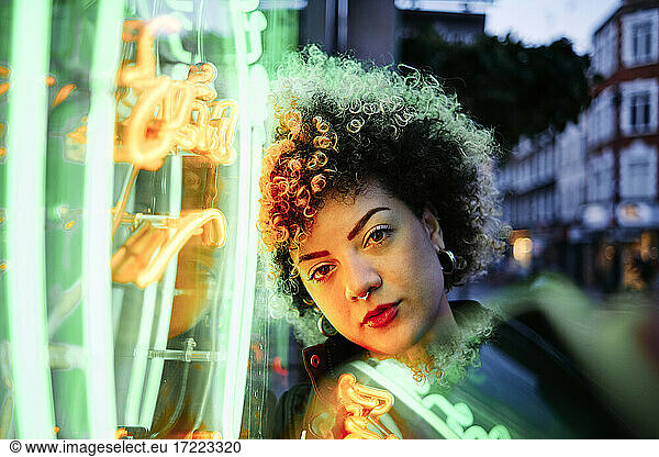 Hipster-Frau lehnt sich nachts an Neonröhren