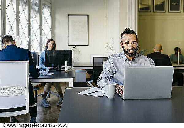 Hipster Geschäftsmann arbeitet am Laptop am Schreibtisch im Büro