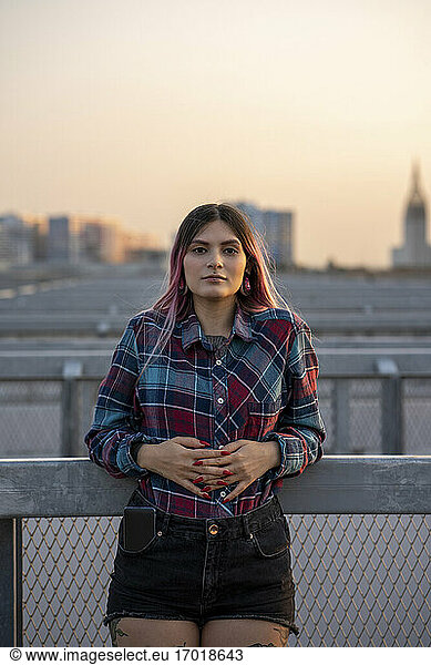 Hipster junge Frau lehnt bei Sonnenuntergang am Geländer