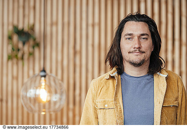 Hipster man with long hair standing in front of wall
