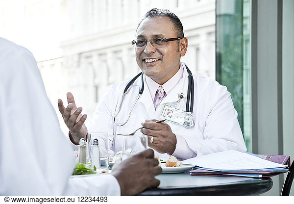 Hispanic man doctor in a lunch discussion with a colleague.