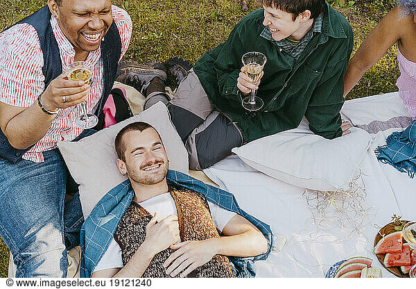 Hochformatige Ansicht von Freunden aus der LGBTQ-Gemeinschaft  die sich bei einer Dinnerparty im Hinterhof amüsieren