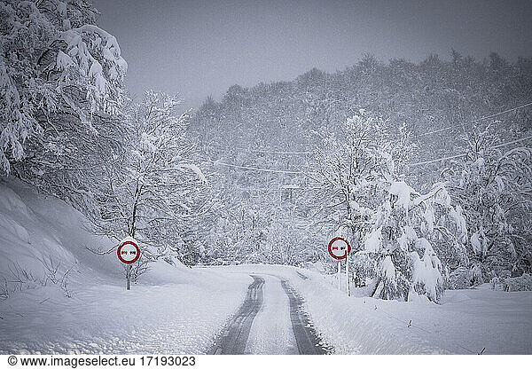 Hochgebirgsstraße und Verkehrszeichen mitten im Schneefall