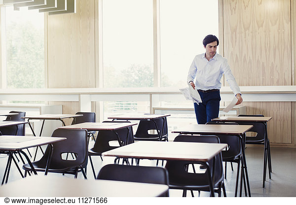 Hochschulprofessor beim Sammeln von Tests auf Tischen im Klassenzimmer