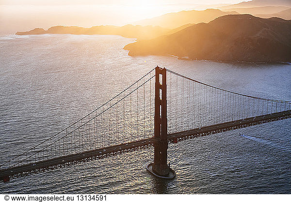 Hochwinkelansicht der Golden Gate Bridge über dem Meer bei Sonnenuntergang