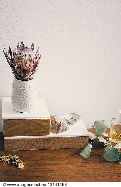 Hochwinkelansicht einer Blumenvase mit Schmuck und Schönheitsprodukten auf einem Holztisch
