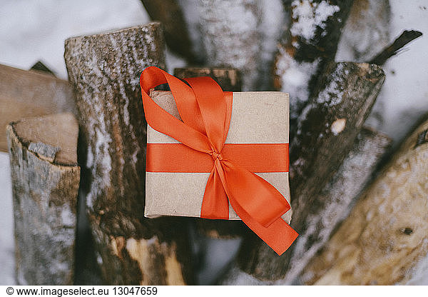 Hochwinkelansicht einer Geschenkverpackung auf Baumstämmen im Winter