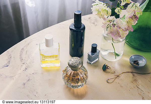 Hochwinkelansicht von Schönheitsprodukten mit Schmuck durch Blumenvase auf dem Tisch