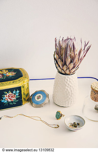 Hochwinkelansicht von Schatulle und Schmuck bei Blumenvase auf Tisch