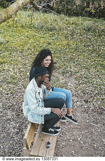 Hochwinkelaufnahme eines glücklichen Paares auf einer Parkbank sitzend
