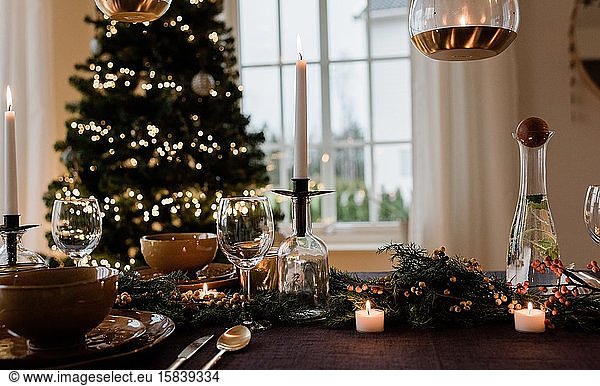 hohe Kerze auf einem festlich gedeckten Esstisch zu Weihnachten