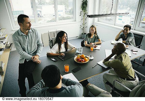 Hoher Blickwinkel von lächelnden multirassischen Geschäftskollegen bei der Planung einer Sitzung im Büro