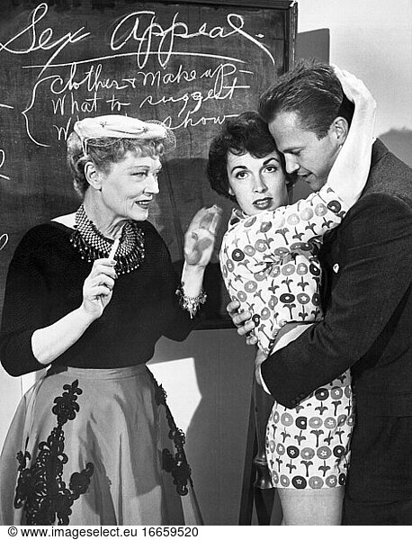 Hollywood  Kalifornien  3. Dezember 1954.
Gilda Gray  die Ziegfeld-Shimmy-Königin der wilden Zwanziger  wurde engagiert  um vier schwülen Sirenen beizubringen  wie man sich für den Film Kiss Me Deadlly   einen Mickey-Spillane-Thriller  sexy verhält. Hier zeigt sie der Schauspielerin Maxine Cooper  wie man Ralph Meeker im Film umarmt.