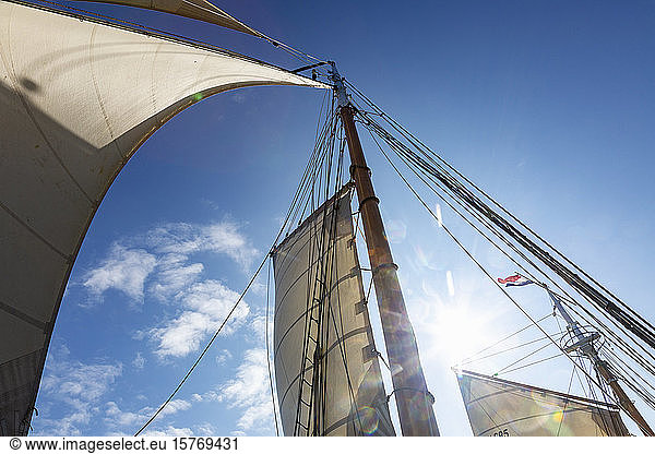 Holz und Mast und Segelboot segeln unter sonnigem blauen Himmel
