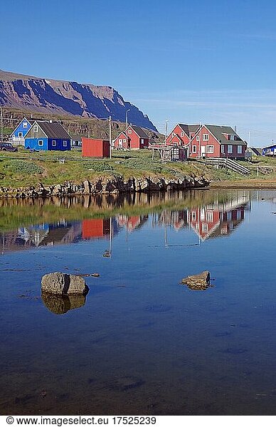 Holzhäuser spiegeln sich an einem ruhigen Sommerabend in einem Gewässer  vulkanisches Gestein  Diskoinsel  Diskobucht  Qeqertarsuaq  Arktis  Grönland  Arktis  Dänemark  Nordamerika