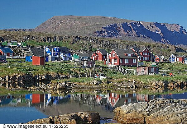 Holzhäuser spiegeln sich an einem ruhigen Sommerabend in einem Gewässer  vulkanisches Gestein  Diskoinsel  Diskobucht  Qeqertarsuaq  Arktis  Grönland  Arktis  Dänemark  Nordamerika