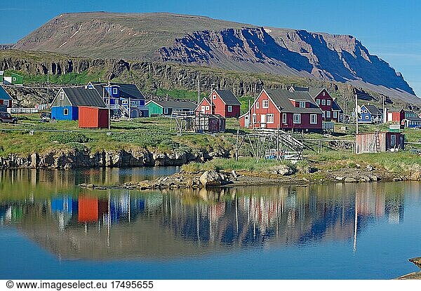 Holzhäuser spiegeln sich in einem ruhigen Gewässer  vulkanisches Gestein  Diskoinsel  Diskobucht  Qeqertarsuaq  Arktis  Grönland  Arktis  Dänemark  Nordamerika