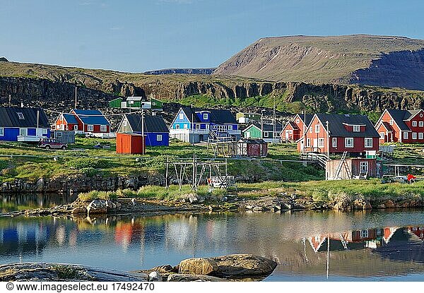 Holzhäuser spiegeln sich in einem ruhigen Gewässer  vulkanisches Gestein  Diskoinsel  Diskobucht  Qeqertarsuaq  Arktis  Grönland  Dänemark  Nordamerika