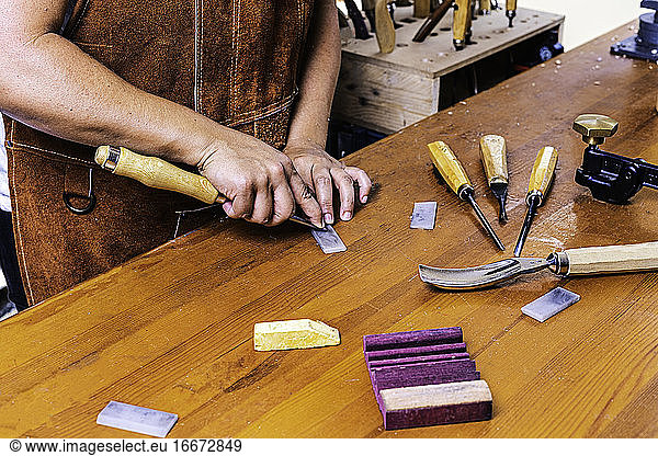 Holzhandwerkerin schärft Werkzeug mit Stein