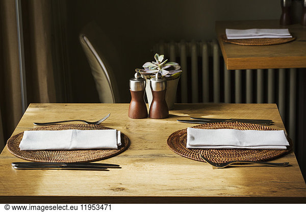 Holztischset mit Platzdeckchen  Servietten und Besteck in einem Restaurant.