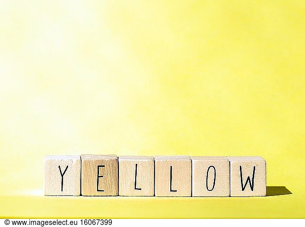 Holzwürfel mit dem Wort Gelb auf gelbem Hintergrund  fröhliche Sommer-Konzept bunte Retro-Design Nahaufnahme.