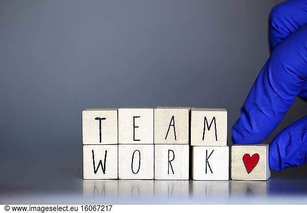 Holzwürfel mit der Aufschrift Teamarbeit für ein Geschäftskonzept oder für Krankenschwestern oder Ärzte Covid-19  Coronavirus  Arbeit in Teams weltweit Herzsymbol.