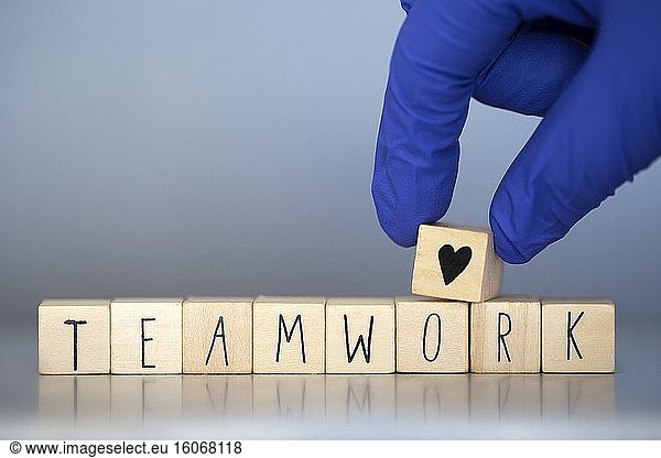 Holzwürfel mit der Aufschrift Teamarbeit für ein Geschäftskonzept oder für Krankenschwestern oder Ärzte Covid-19  Coronavirus  Arbeit in Teams weltweit Herzsymbol.