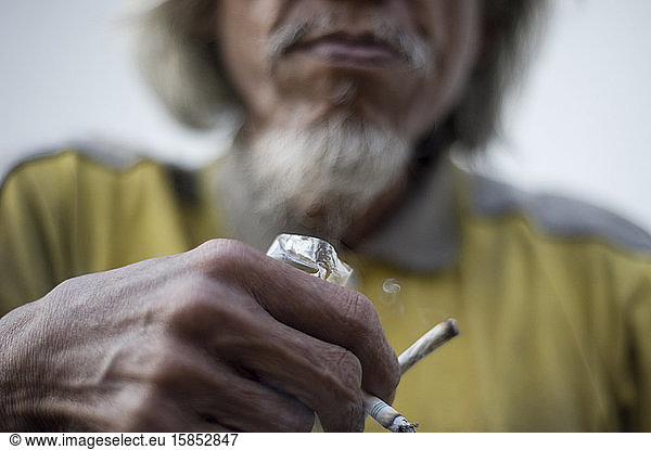 Homeless man holding a cigarette and a joint