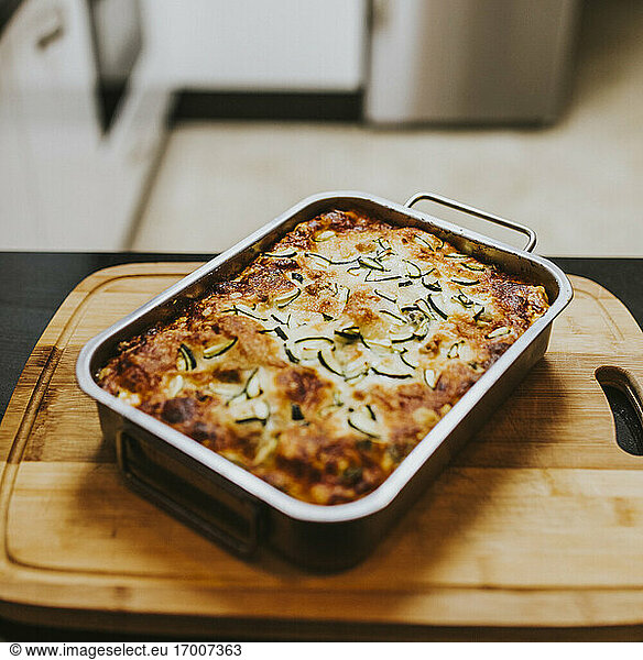 Homemade cooked lasagna with zucchini in tray on cutting board at home
