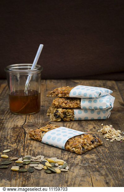 Homemade granola bars and a glass of honey on wood