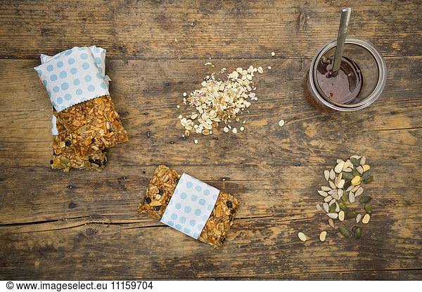 Homemade granola bars and a glass of honey on wood