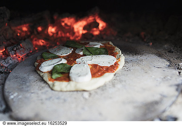 Homemade margherita pizza on stone in hot pizza oven