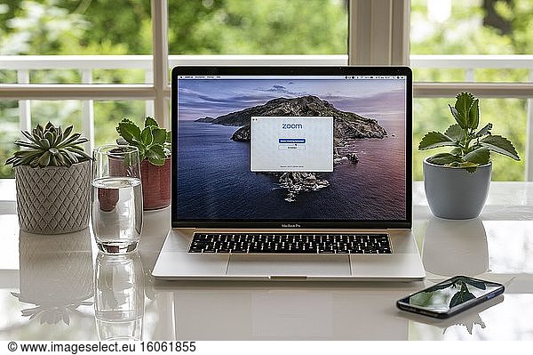 Homeoffice mit Laptop  Apple MacBook Pro und iPhone X am Schreibtisch  mit Programm Zoom für Videokonferenz  Deutschland  Europa