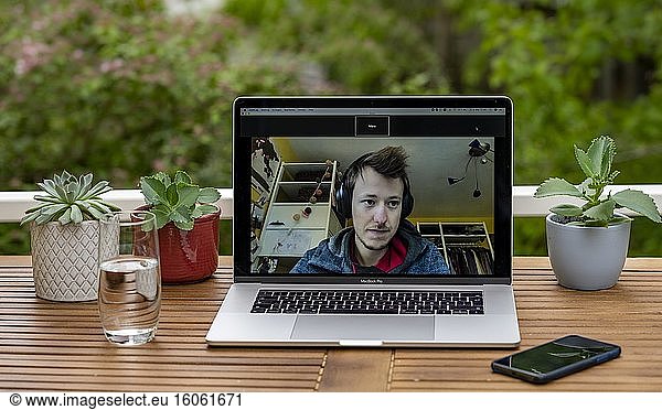 Homeoffice mit Laptop  Apple MacBook Pro und iPhone X am Schreibtisch  mit Programm Zoom während einer Videokonferenz  Deutschland  Europa