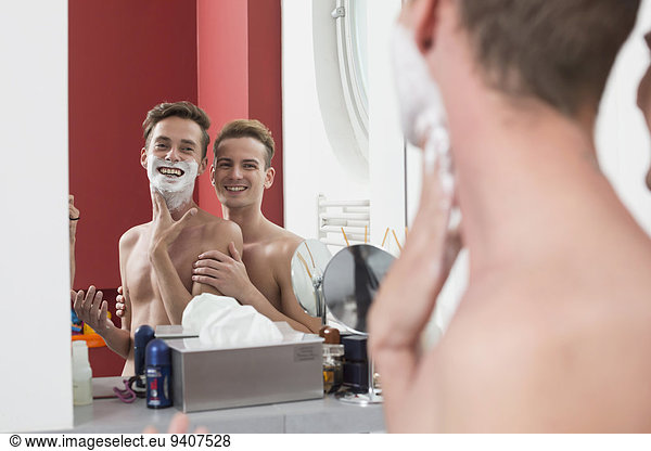 Homosexual couple caress each other while shaving  smiling