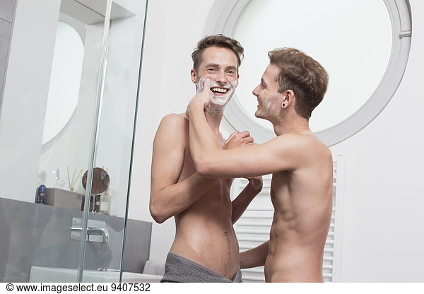Homosexual couple having fun while shaving,  smiling