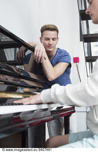 Homosexual couple playing piano, smiling