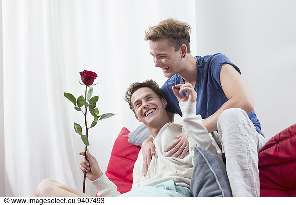 Homosexual couple with red rose,  smiling