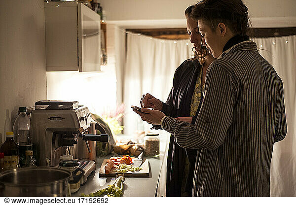 Homosexuelles Paar folgt Telefonrezept in der Küche und kocht gesundes Abendessen