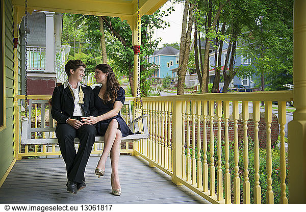Homosexuelles Paar sieht sich an  während es auf der Schaukel auf der Veranda sitzt