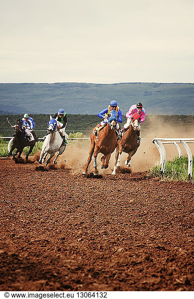 Horse race on field against clear sky