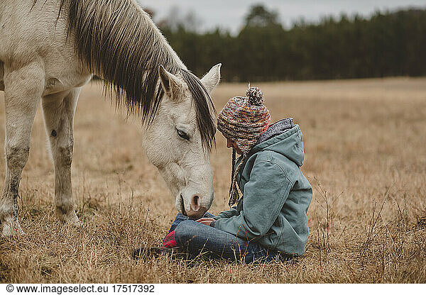 Horse smelling teen girls hands