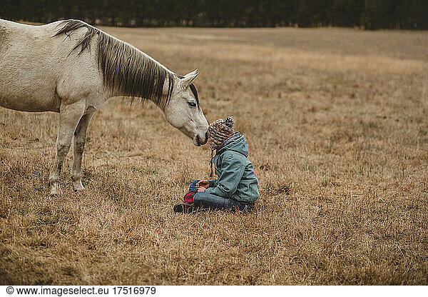 Horse standing in pasture with girl