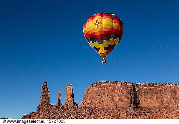 Hot air balloon flies in front of the Three Sisters  Balloon Festival in the Monument Valley  Monument Valley Navajo Tribal Park  Arizona  USA  North America